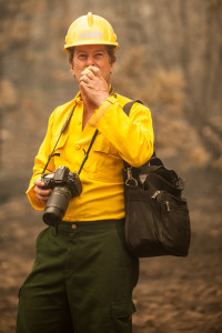 A writer/photographer from a firefighter magazine in Germany enjoys an apple as he watches the fire.